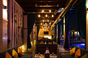 A modern interior with a bar area, seating, and a pool view. - The Landmark Hotel (Kanpur)