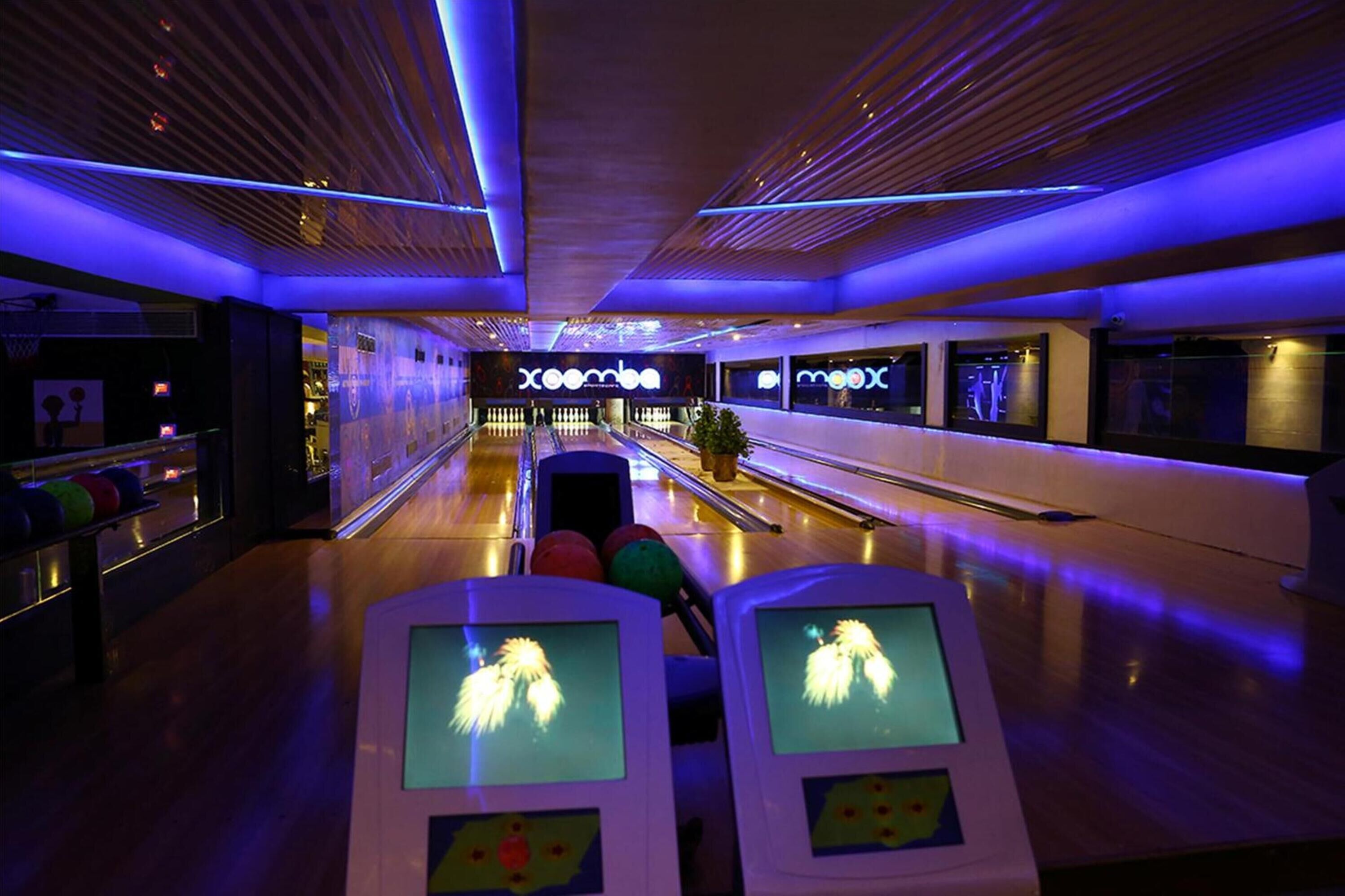 A bowling alley with multiple lanes, neon lighting, and a wooden ceiling.