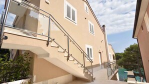 A beige building with a staircase leading to a balcony. - Holiday apartment with terrace 200 m from the beach (Primošten)