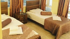 A hotel room with two beds, a nightstand, and a window with curtains. - Hotel Guesthouse Lola (Batumi)
