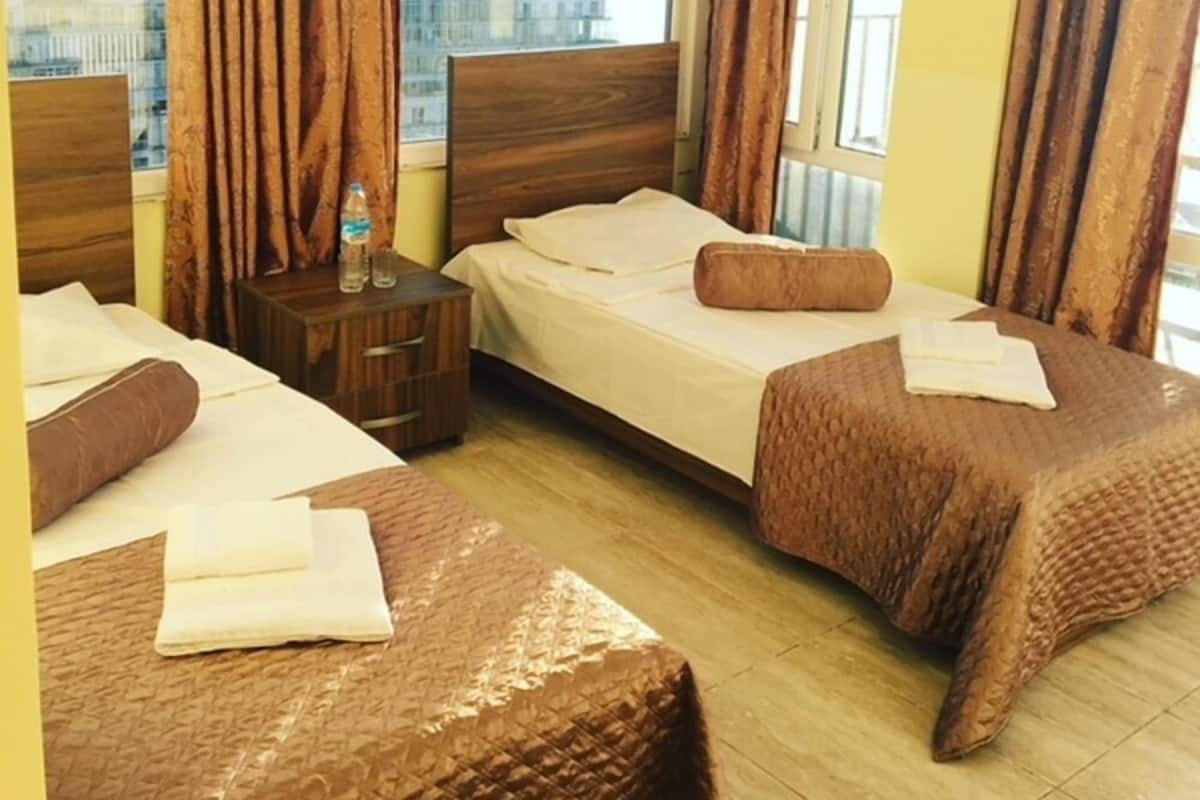 A hotel room with two beds, a nightstand, and a window with curtains.