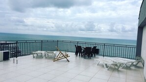 A balcony with a view of the sea, white chairs, and a table. - Hotel Guesthouse Lola (Batumi)