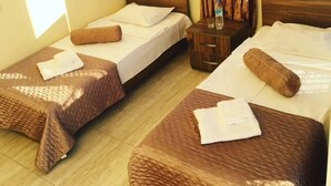 A hotel room with two single beds, a wooden headboard, a small wooden nightstand, and a window with curtains. - Hotel Guesthouse Lola (Batumi)