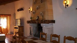 Un comedor con una mesa y sillas de madera, una chimenea y lámparas fijadas a la pared.