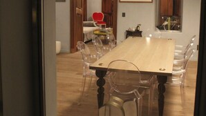 A dining area with a wooden table and clear chairs, a pendant light, and a wooden door leading to another room. - Live a unique 'provencale' experience in the heart of the Luberon (Apt)