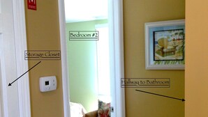 Un couloir avec un placard de rangement, une chambre et un autre couloir menant à la salle de bain.