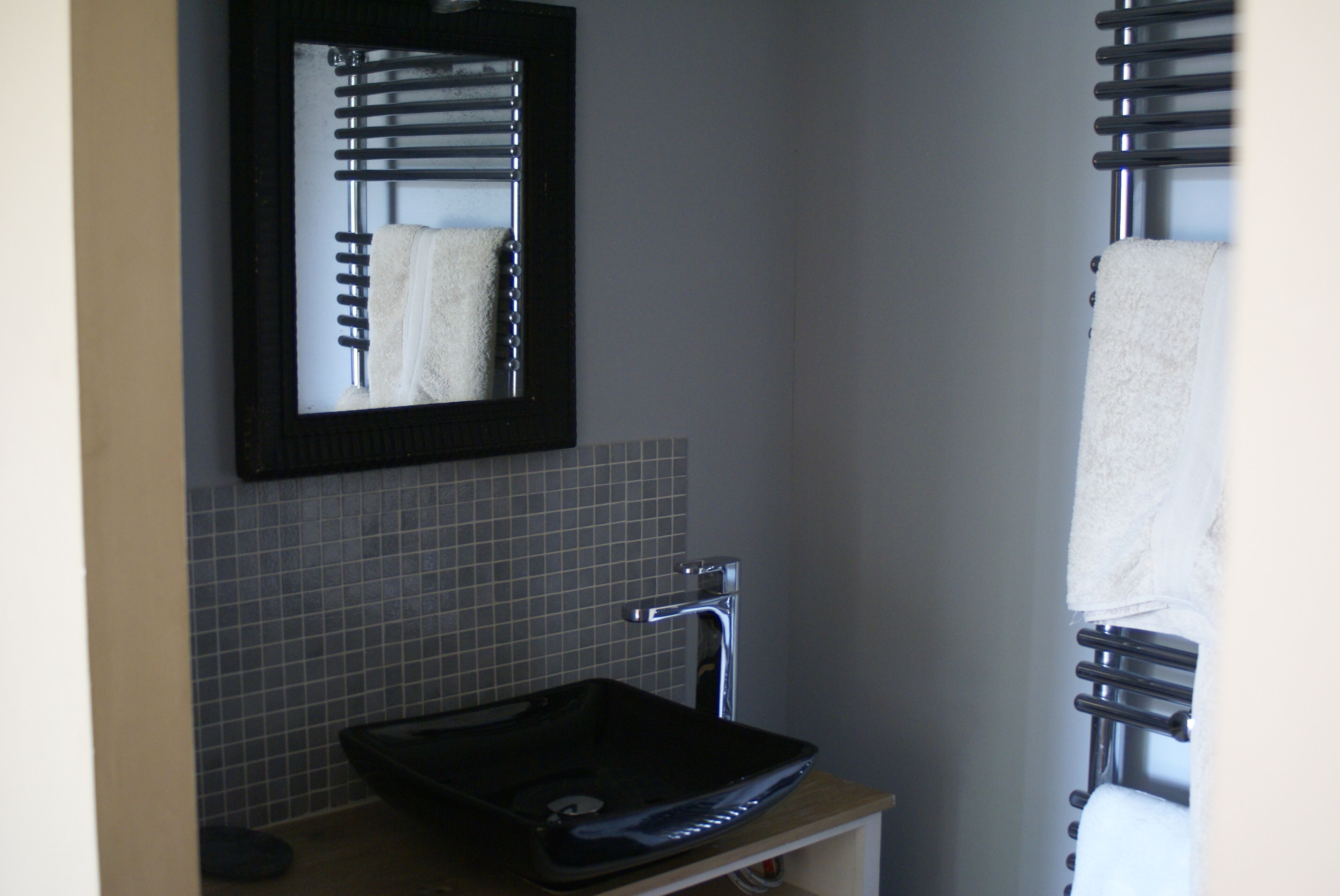Une salle de bain avec un lavabo noir, un miroir et un porte-serviettes.