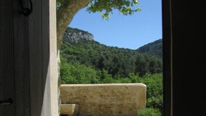 An open doorway leading to a courtyard with a stone wall and a view of a mountainous landscape.