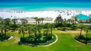 A beach resort with a white sandy beach, palm trees, and a clear blue ocean.