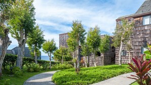 A residential area with wooden houses, a curved pathway, and a sign labeled "Cluster G".