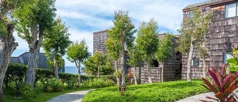 A residential area with wooden houses, a curved pathway, and a sign labeled "Cluster G".