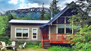 A cabin with a porch, two windows, and a staircase leading to the entrance.