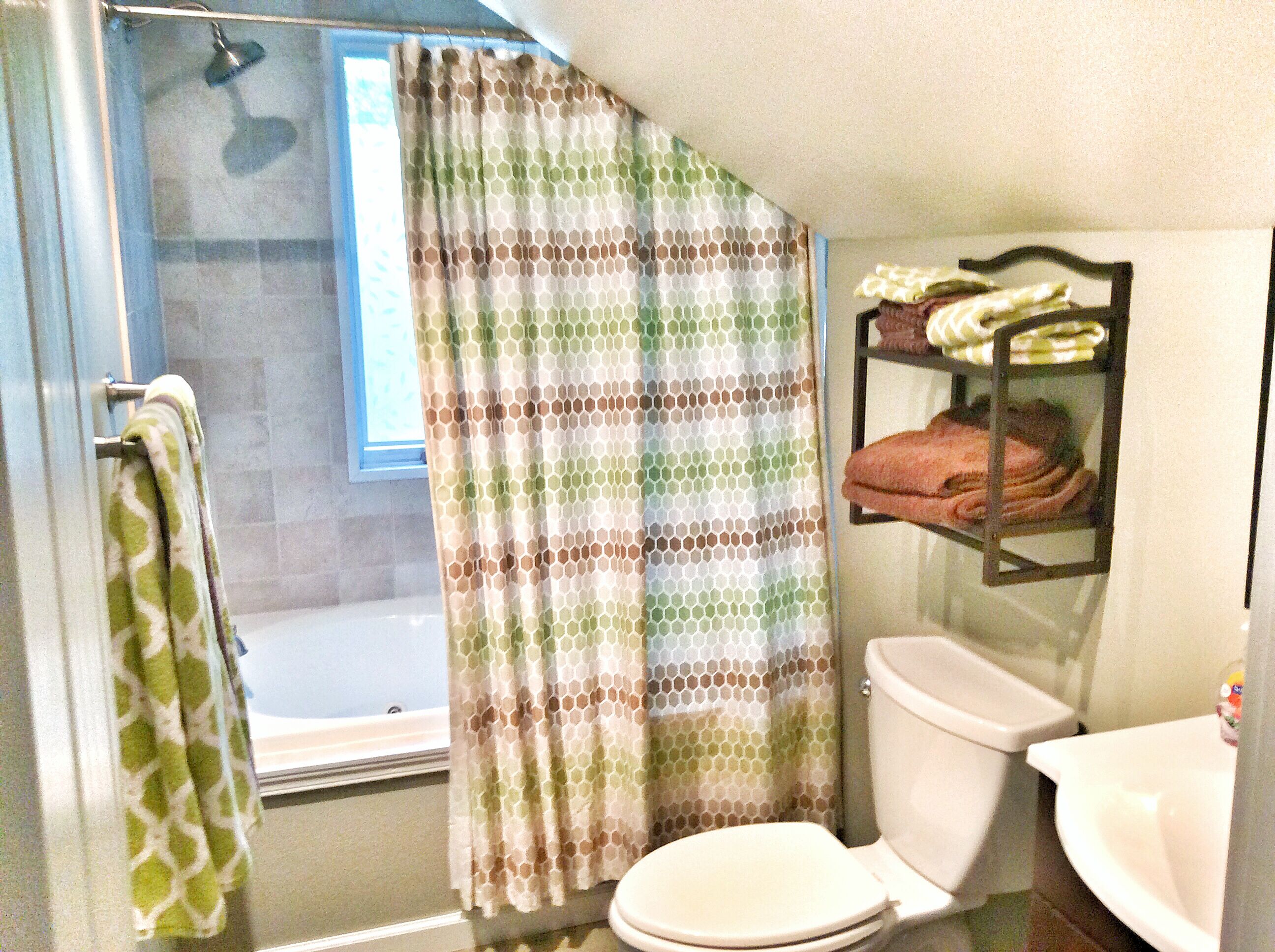 A bathroom with a shower, toilet, and a shelf with towels.