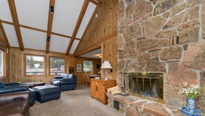 Una sala de estar acogedora con chimenea de piedra, sofás de cuero y techo de madera.