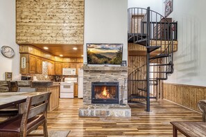 Un interior acogedor con chimenea de piedra, zona de comedor de madera y una escalera de caracol.