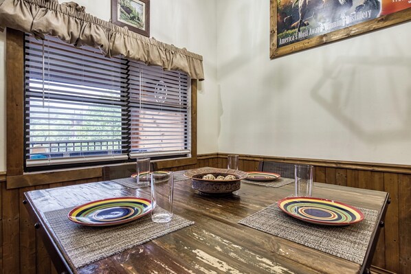 Un comedor con una mesa de madera, platos coloridos y un tazón de aperitivos.