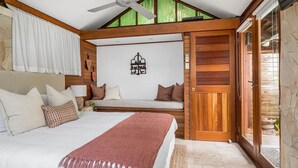 Un dormitorio con cama, una banca y una puerta de madera.