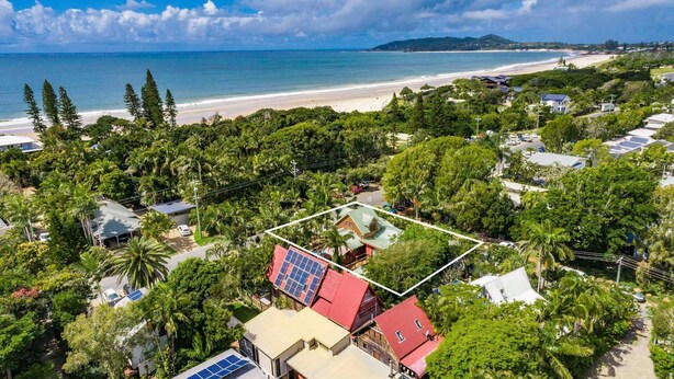 Zona residencial costera con casas, paneles solares y una playa al fondo.