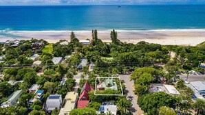 Vista aérea de una zona costera con playa, abundante vegetación y diversos edificios.