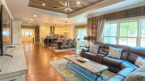A spacious living room with a leather sofa, a coffee table, and a dining area in the background. - Herber Haus, Historic Luxury • Walk to Main • Game Room (Fredericksburg)