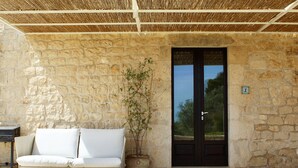 Un bâtiment en pierre avec une porte noire, un canapé blanc et une plante en pot.