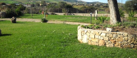 Un muro de piedra con un campo cubierto de hierba y un árbol en primer plano.