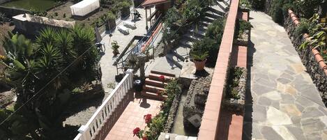 A multi-level outdoor terrace with stone flooring, potted plants, and a water feature.