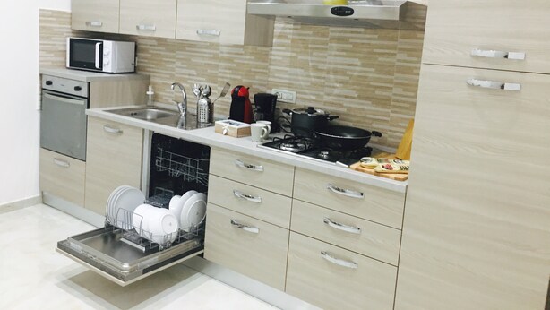 A modern kitchen with a dishwasher, microwave, stove, and cabinets.