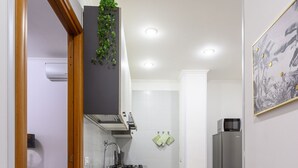 A compact kitchen with a built-in stove, a microwave, and a refrigerator. - Barsanti Apartment (Roma)