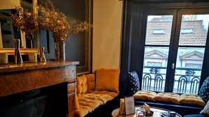 Ett mysigt vardagsrum med en öppen spis, en soffa, ett soffbord och utsikt över omgivningen.