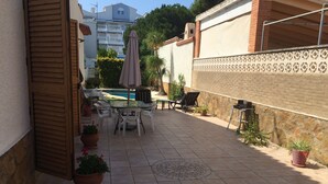 Eine Terrasse mit Tisch und Stühlen, einem Pool und Kübelpflanzen.