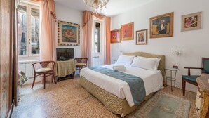 A bedroom with a bed, a desk, chairs, and artwork on the walls.