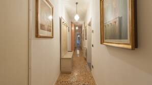 A hallway with framed artwork on the walls, a bench, and a light fixture.