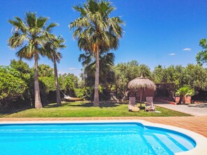 A swimming pool surrounded by palm trees and a thatched-roof hut. - Cozy house with pool and private gardens. (Alhaurin el grande)