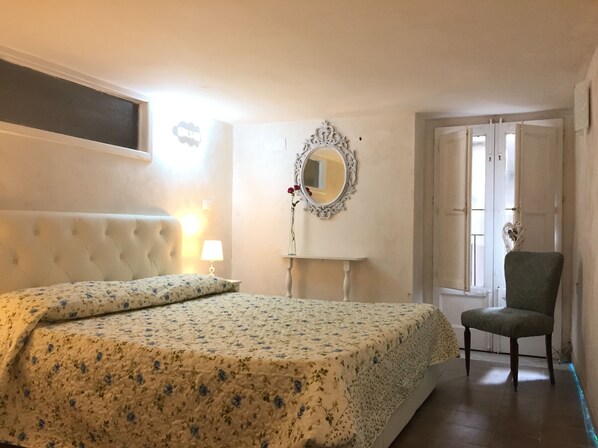 A bedroom with a bed, a chair, a mirror, and a door.
