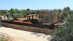 A rustic stone building with a wooden deck, surrounded by olive trees and a stone wall. - TRULLO WITH POOL SEA VIEW - GALLIPOLI - SOUTH TOWER - JUST RENOVATED (Torre Suda)