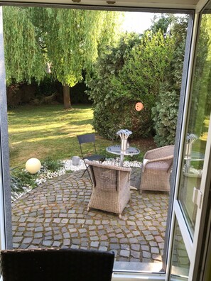 A patio with wicker furniture, a round table, and a small fountain.