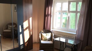 A bedroom with a large bed, a chair, a table, a mirror, and a window with curtains. - Holiday house in the nature reserve Schwalmtal  (Schwalmtal)