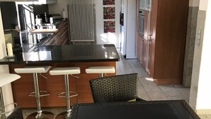 A modern kitchen with a central island, bar stools, and a dining area with a table and chairs. - Holiday house in the nature reserve Schwalmtal  (Schwalmtal)