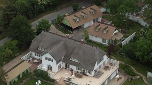 Ein großes, zweistöckiges Haus mit geräumiger Terrasse und gepflegtem Rasen.