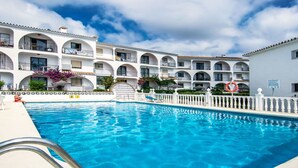 Un hôtel doté d’une piscine, d’une façade blanche, de balcons et offrant une vue sur un ciel dégagé.