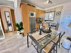 A modern kitchen with wooden cabinets, stainless steel appliances, and a glass dining table.
