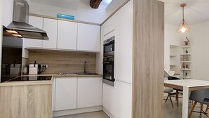 Una cocina moderna con armarios blancos, encimera de madera y horno empotrado.