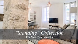 Una sala moderna con una pared de acento de piedra, un sofá, un televisor e iluminación colgante.