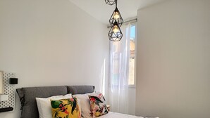 Un dormitorio moderno con una cama grande, cabecera gris y almohadas coloridas.