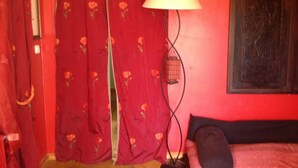 A room with red walls, a bed with a black headboard, a red curtain with floral patterns, and a floor lamp. - Asian pavilion one minute from the beach (Loctudy)