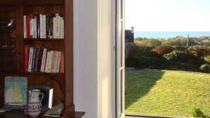 Une bibliothèque remplie de livres, dont un livre sur la voile, un pichet et une carte postale.