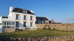 Une maison à deux étages avec un mur en pierre et une pelouse verdoyante.