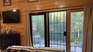 Une chambre confortable avec un grand lit, une télévision et une porte-fenêtre coulissante donnant sur un balcon.