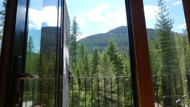 Une pièce dotée d’une grande fenêtre donnant sur une région montagneuse couverte de forêts.
